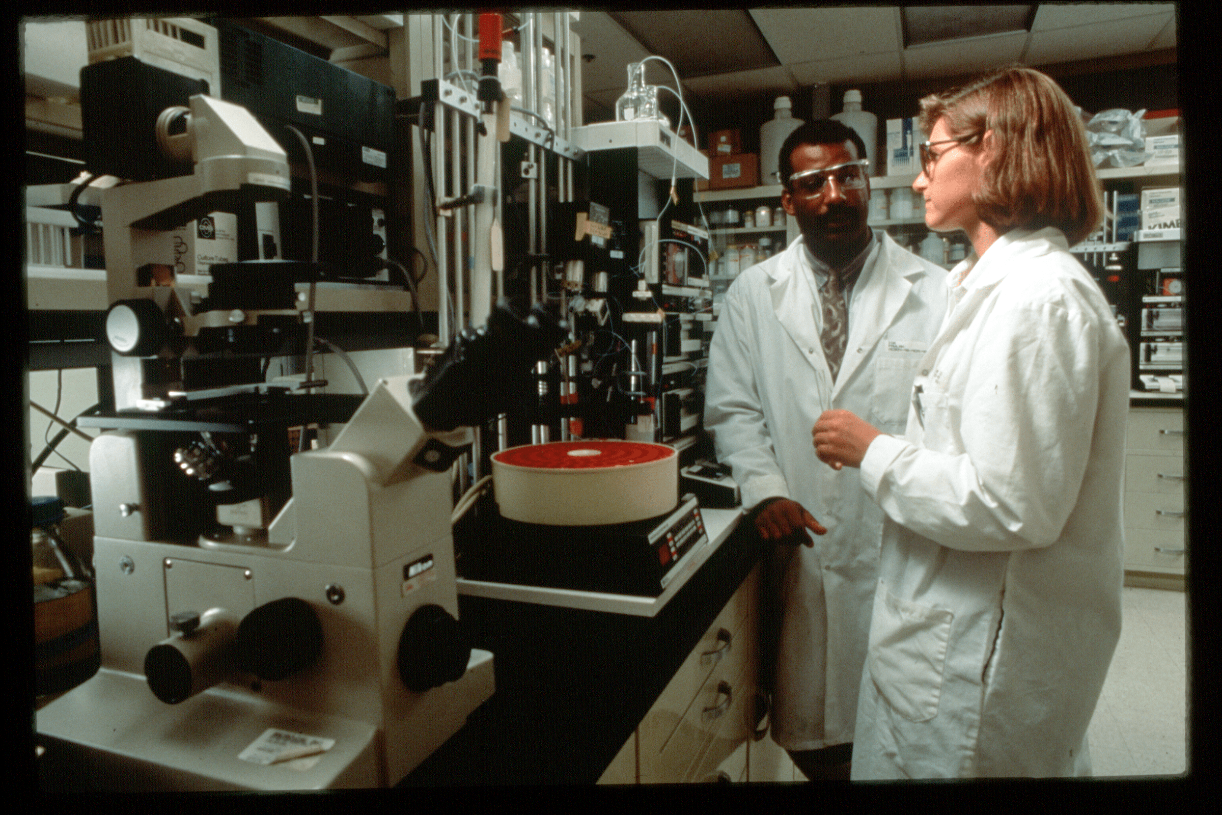two Lilly scientists wearing white lab coats in lab